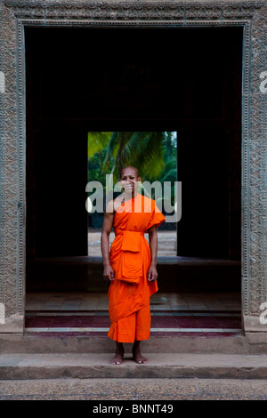 Monaco novizio che pongono nel telaio della porta di un wat - provincia di Kandal, Cambogia Foto Stock