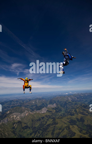 Skydivers sono battenti testa fino all'interno di un team in sit fly posizione su uno spettacolare paesaggio di montagna con oltre 120 mph velocità. Foto Stock