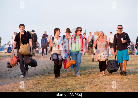 I frequentatori del festival di arrivare al Glastonbury festival che trasportano attrezzature per il campeggio. Il Somerset, Inghilterra, Regno Unito. Foto Stock