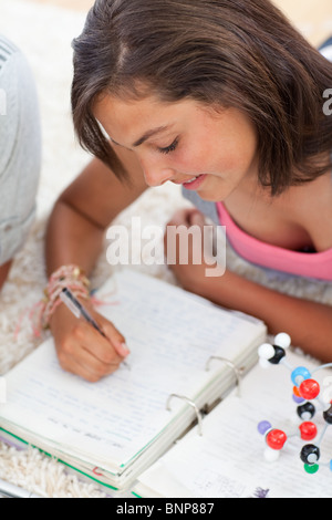 Bella adolescente facendo i compiti sul pavimento Foto Stock