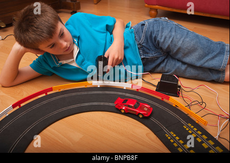 Un modello rilasciato dieci anno vecchio ragazzo giocando con un Hornby Scalextric racing car set game del Regno Unito Foto Stock