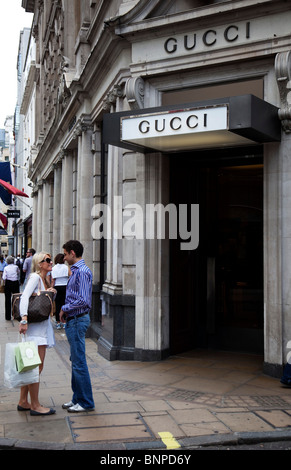 Gli amanti dello shopping pass high end negozi di Londra è Bond Street. Conosciuto per i suoi esclusivi negozi di moda. Gucci. Foto Stock