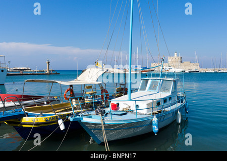 Barche di fronte al vecchio Agios Nikolaos fortezza e faro di Mandrachi Harbour, Rodi, Rodi, Grecia Foto Stock