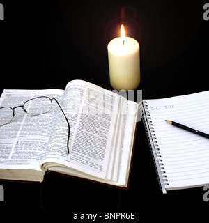 La Bibbia, candela e note book per mostrare a tarda notte lo studio della bibbia Foto Stock