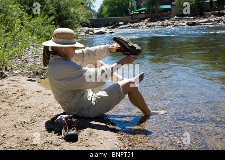 Donna mettendo su le scarpe e le calze dopo il guado del fiume Arkansas, Salida, Colorado, STATI UNITI D'AMERICA Foto Stock