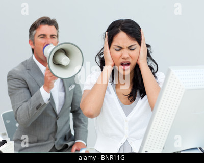 Furious manager gridando in un megafono in un collega le orecchie Foto Stock