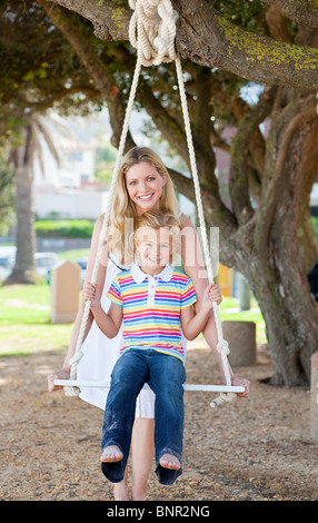 Madre premurosa spingendo la figlia su un altalena Foto Stock