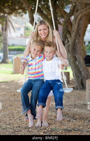 Sorridente madre ed i suoi figli swinging Foto Stock