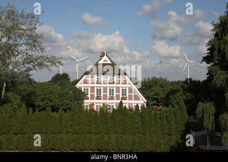 Un graticcio casa colonica con il tetto di paglia con una wind farm in background, vicino Ochsenwerder, a est di Amburgo, Germania, Europa Foto Stock