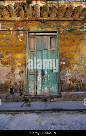 Verde porta rustica su muri cadenti in eroso facciata di edificio in Old Havana, Cuba. Foto Stock