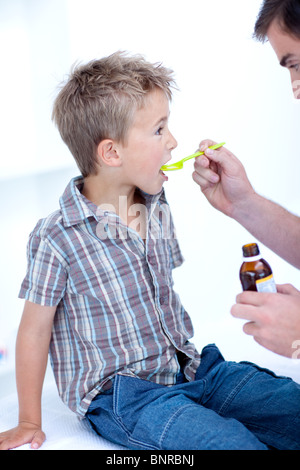 Bambino prendendo medicine per la tosse Foto Stock