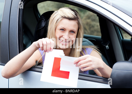 Allegro giovane driver femmina sistemando il suo segno L Foto Stock