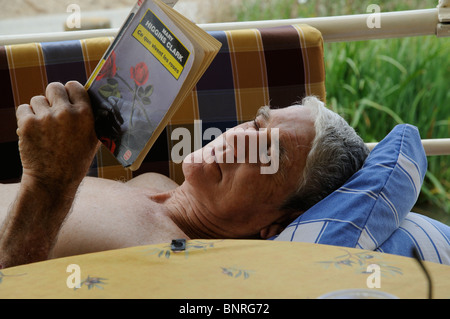 Ritratto di un uomo di addormentarsi durante la lettura di un romanzo Foto Stock