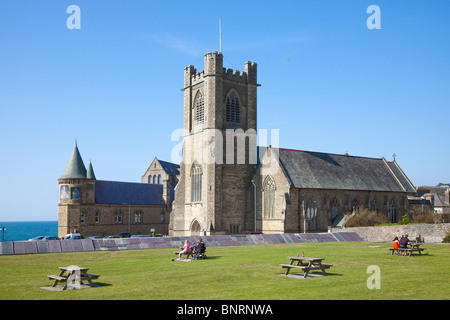 Le persone sedute a panche per picnic all'esterno la chiesa di San Michele e vecchi edifici universitari Aberystwyth Wales UK Foto Stock