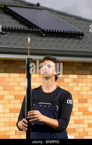 Artigiano qualificato installazione solare di acqua calda sistema a una casa, Nelson, Nuova Zelanda, la città con la più alta ore di sole Foto Stock