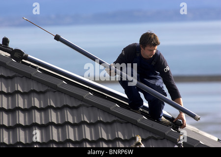 Artigiano qualificato installazione solare di acqua calda sistema a una casa, Nelson, Nuova Zelanda, la città con la più alta ore di sole Foto Stock