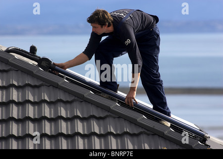 Artigiano qualificato installazione solare di acqua calda sistema a una casa, Nelson, Nuova Zelanda, la città con la più alta ore di sole Foto Stock