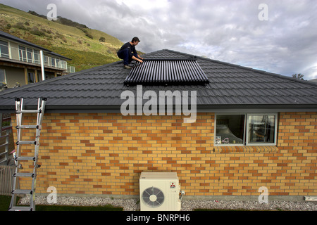 Artigiano qualificato installazione solare di acqua calda sistema a una casa, Nelson, Nuova Zelanda, la città con la più alta ore di sole Foto Stock