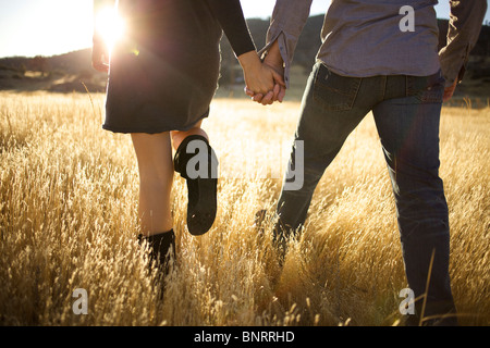 Bassa colpo di coppia del corpo tenendo le mani e a piedi in un campo aperto. Foto Stock