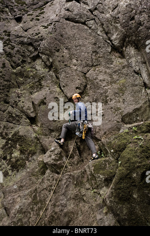Un scalatore di piombo delle pause durante la salita. Foto Stock