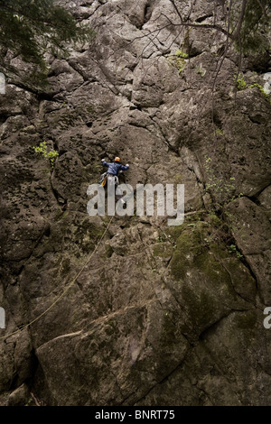 Un scalatore di piombo la scalabilità di una roccia. Foto Stock