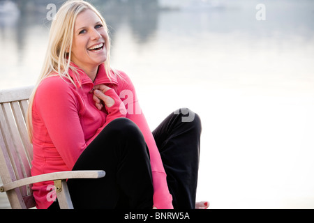 Una giovane donna appendere fuori su una dock sul lago Washington e sorridente alla fotocamera. Foto Stock