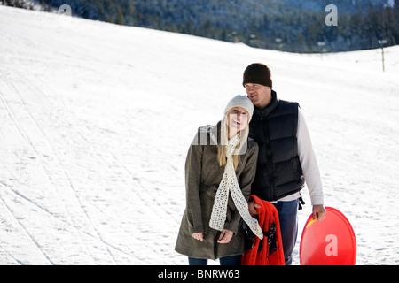 Un uomo e una donna godere di una giornata di attività in slittino in montagna. Foto Stock