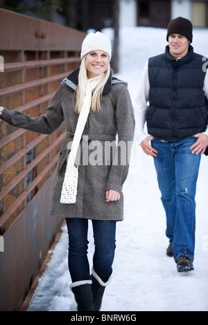 Una coppia giovane vestito caldamente godere ogni altre società in montagna con un lodge in background. Foto Stock