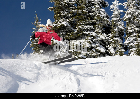 Una donna bionda sci attraverso la polvere in una giornata di sole. Foto Stock