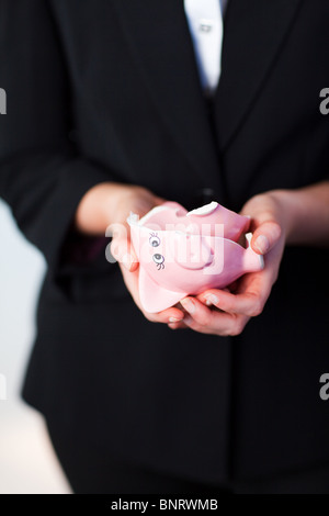 Business donna tenendo la rottura di un salvadanaio Foto Stock