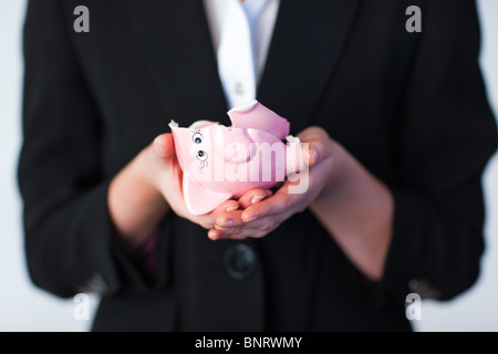 Business donna tenendo la rottura di un salvadanaio Foto Stock