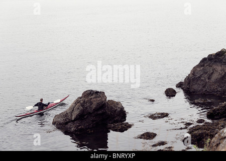Un giovane uomo gode del Puget Sound intorno a San Juan Islands da kayak di mare. Foto Stock