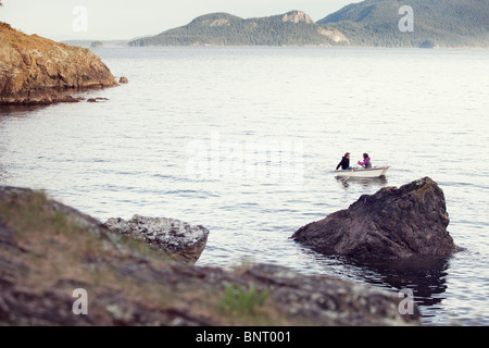 Una giovane coppia riga in Puget Sound da Orcas Island in una piccola barca a remi. Foto Stock