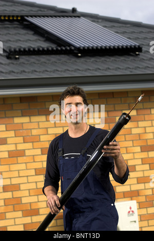 Artigiano qualificato installazione solare di acqua calda sistema a una casa, Nelson, Nuova Zelanda, la città con la più alta ore di sole Foto Stock