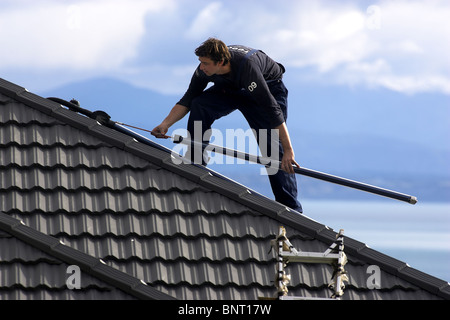 Artigiano qualificato installazione solare di acqua calda sistema a una casa, Nelson, Nuova Zelanda, la città con la più alta ore di sole Foto Stock