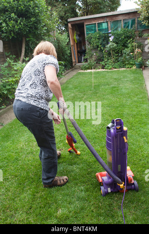 Aspirare il prato con un Dyson aspirapolvere Foto Stock