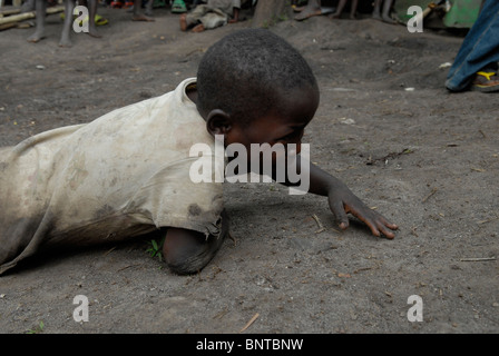 Il giovane ragazzo striscia a terra e grida in un campo per sfollati interni nella provincia del Nord Kivu nella Repubblica Democratica del Congo in Africa Foto Stock