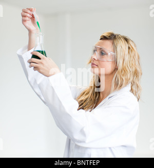 Donna in lapcoat guardando i prodotti chimici Foto Stock