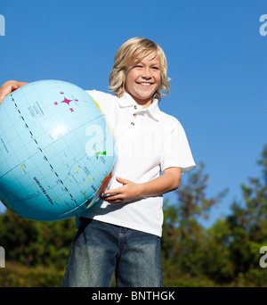 Carino ragazzo giocando con un globo terrestre Foto Stock