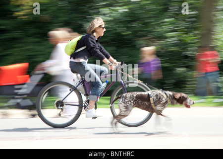 Donna Bicicletta Equitazione mentre passeggiate con il cane Foto Stock