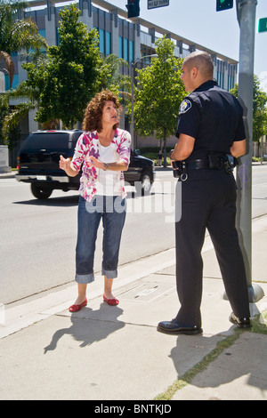 Una donna sostiene con un ispanico funzionario di polizia dopo essere stato fermato per una violazione del codice della strada in Santa Ana CA. Foto Stock