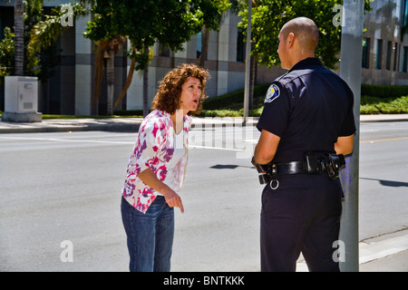 Una donna sostiene con un ispanico funzionario di polizia dopo essere stato fermato per una violazione del codice della strada in Santa Ana CA. Foto Stock