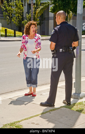 Una donna sostiene con un ispanico funzionario di polizia dopo essere stato fermato per una violazione del codice della strada in Santa Ana CA. Foto Stock