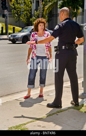 Una donna sostiene con un ispanico funzionario di polizia dopo essere stato fermato per una violazione del codice della strada in Santa Ana CA. Foto Stock