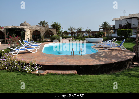 Immagine rilassante del freddo hotel piscina con acqua limpida e alcune sedie, alberi e lounge in tutto Foto Stock