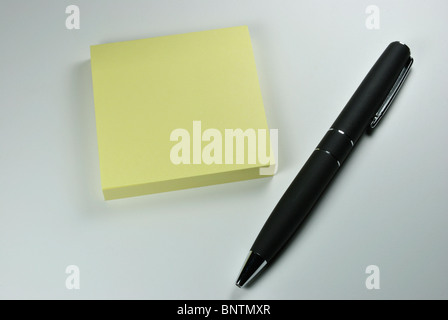 La penna nera posa accanto al libro di sticky notes Foto Stock