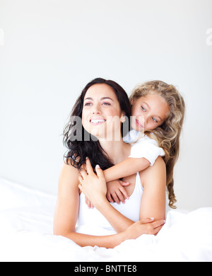 Sorridente madre e figlia abbracciando sul letto Foto Stock