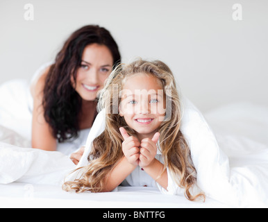 Attraente madre e figlia abbracciando sul letto Foto Stock