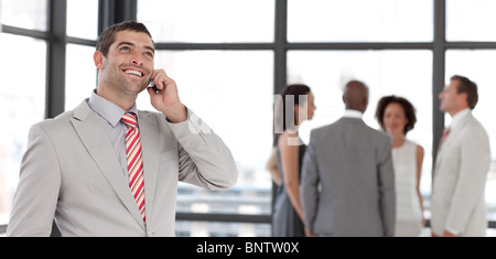 Imprenditore carismatico sul telefono in ufficio con il suo team Foto Stock