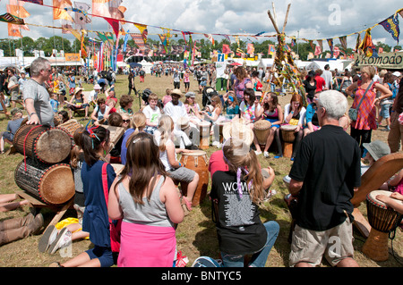 Una classe di drumming tenuto al Womad Festival di musica di Charlton Park WILTSHIRE REGNO UNITO con la folla di festival di famiglie intorno al batterista Foto Stock